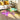Modern iridescent acrylic coffee table with an oval design and geometric legs, featuring a multicoloured surface that changes hues with light. This minimalist piece offers a spacious surface for home décor, made from durable acrylic and includes a protective PVC cover.